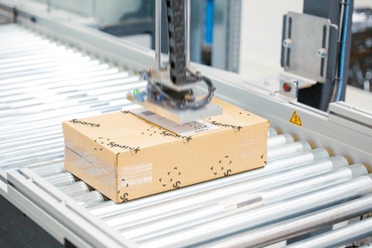 A robotic arm holding a box on a conveyor belt