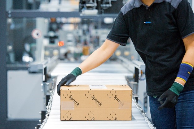 A person holding a box on a conveyor belt